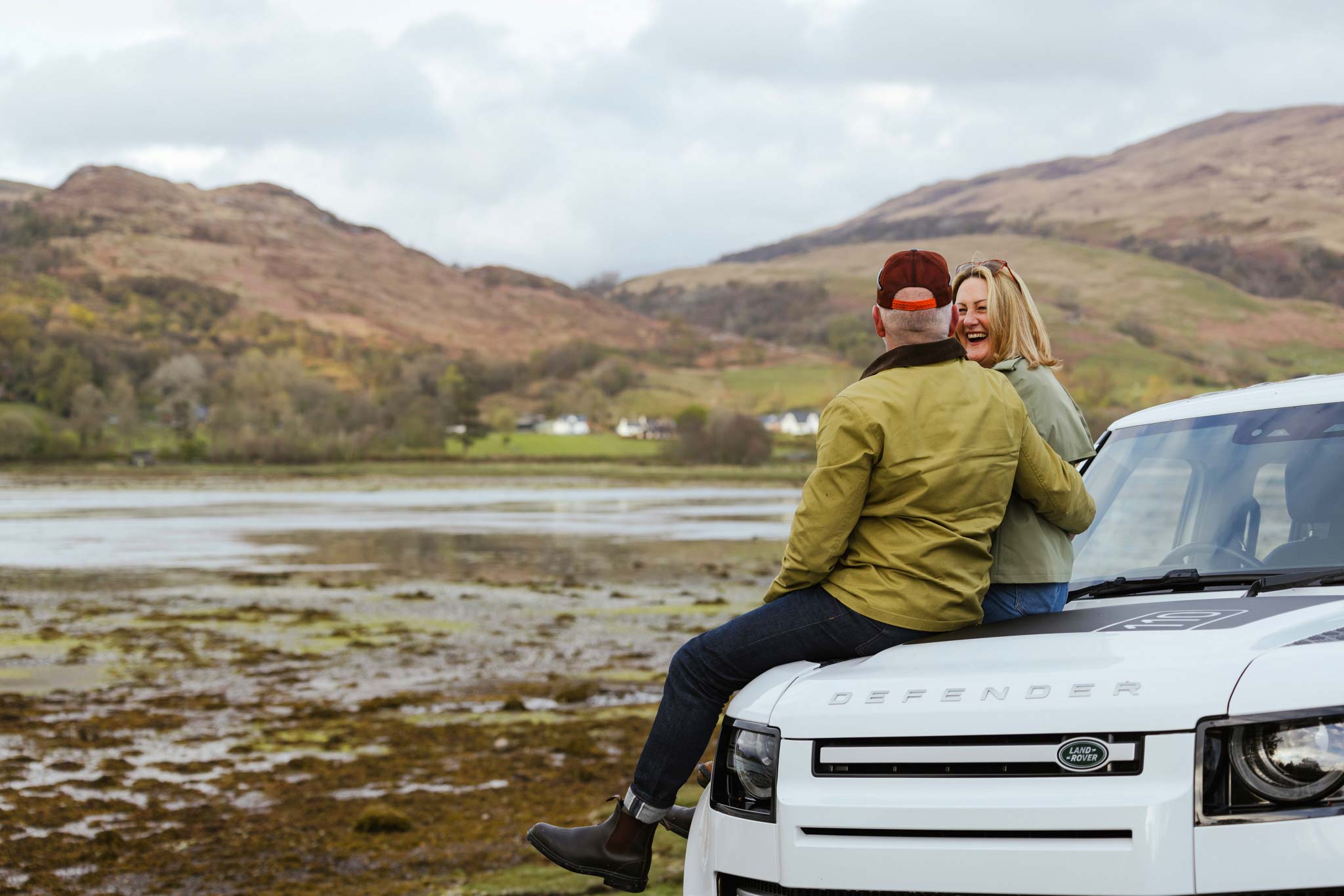 Couple sitting on the bonnet of a Land Rover in Scotland