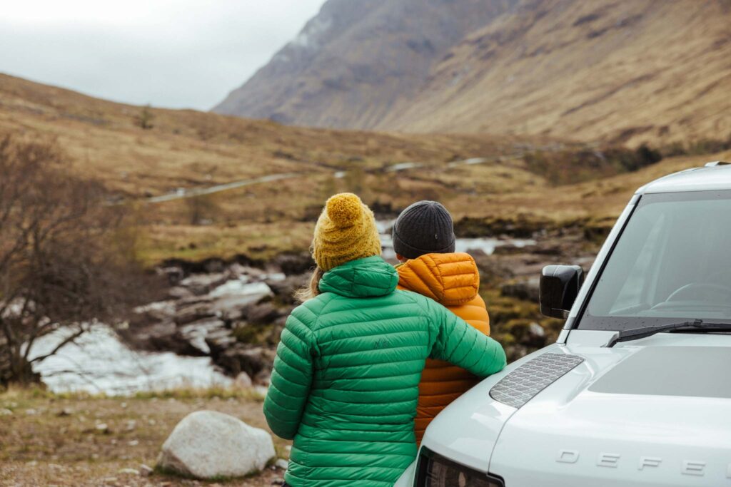 Couple leaning on the bonnet of a Land Rover in Scotland