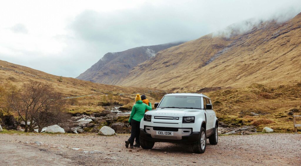 Couple leaning on the bonnet of a Land Rover in Scotland