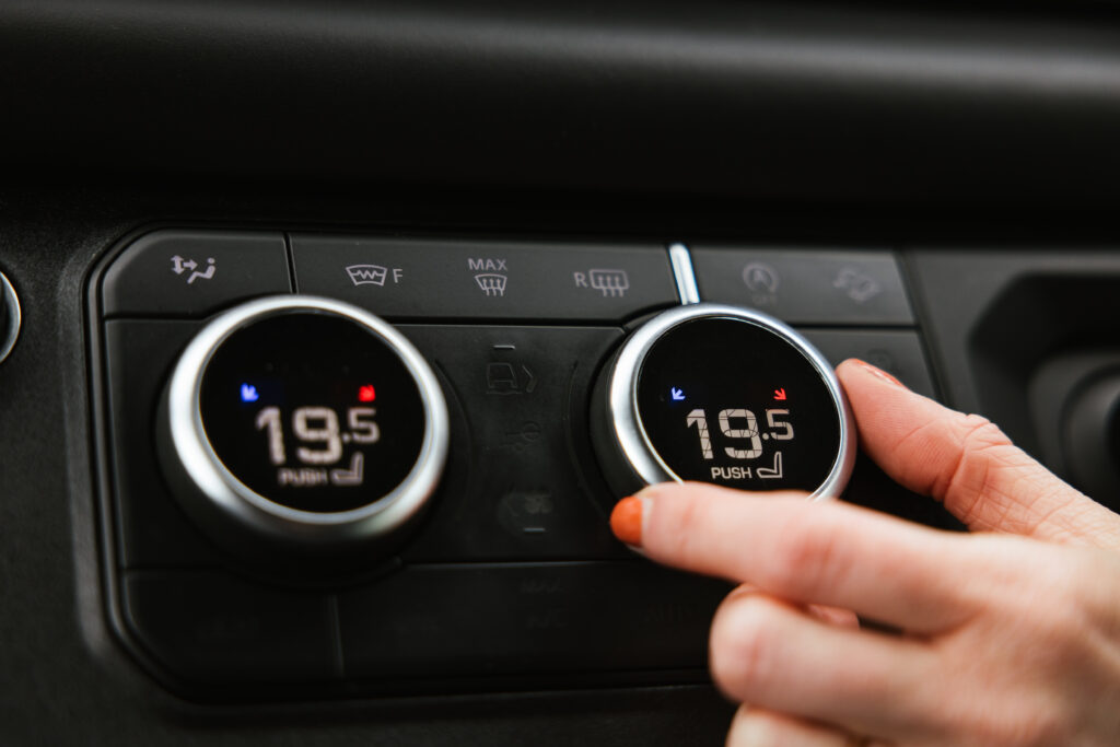 Interior of a Land Rover Defender. Hand turning the temperature gauge