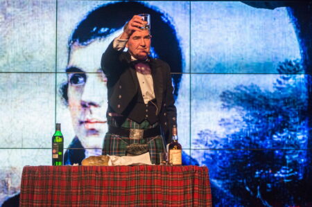 Burns Night speaker raising a whisky glass while addressing the haggis