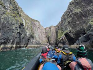 Passengers on a sea safari beneath cliffs near Dingle